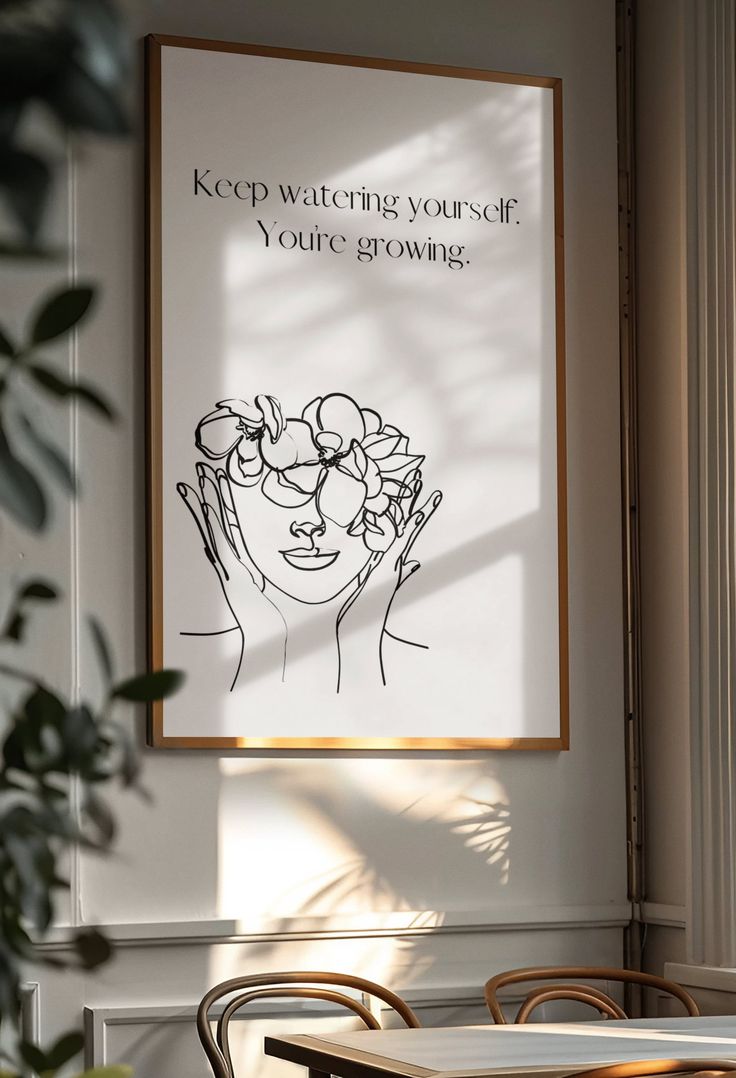 a poster hanging on the wall above a table with chairs and a potted plant