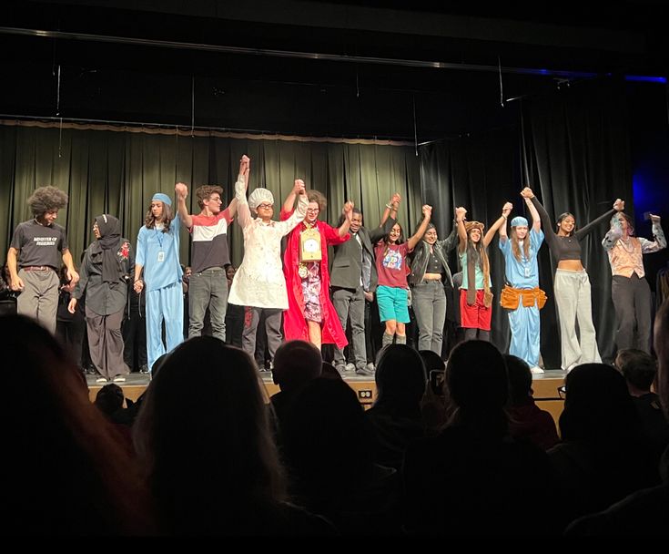 a group of people standing on top of a stage with their hands in the air