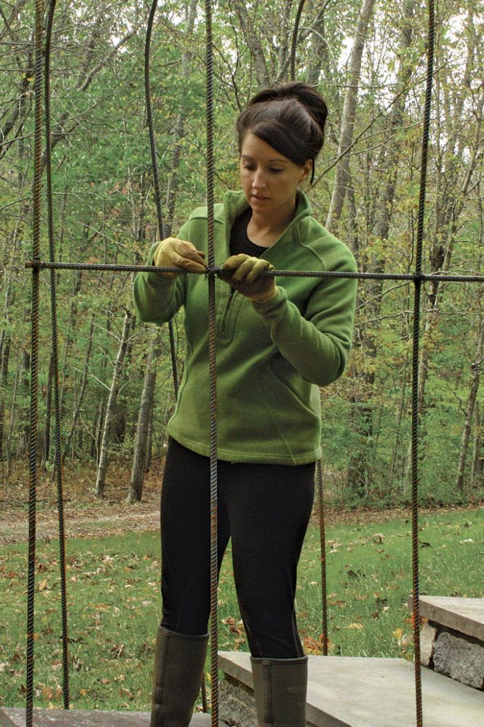 a woman measuring the length of a metal fence