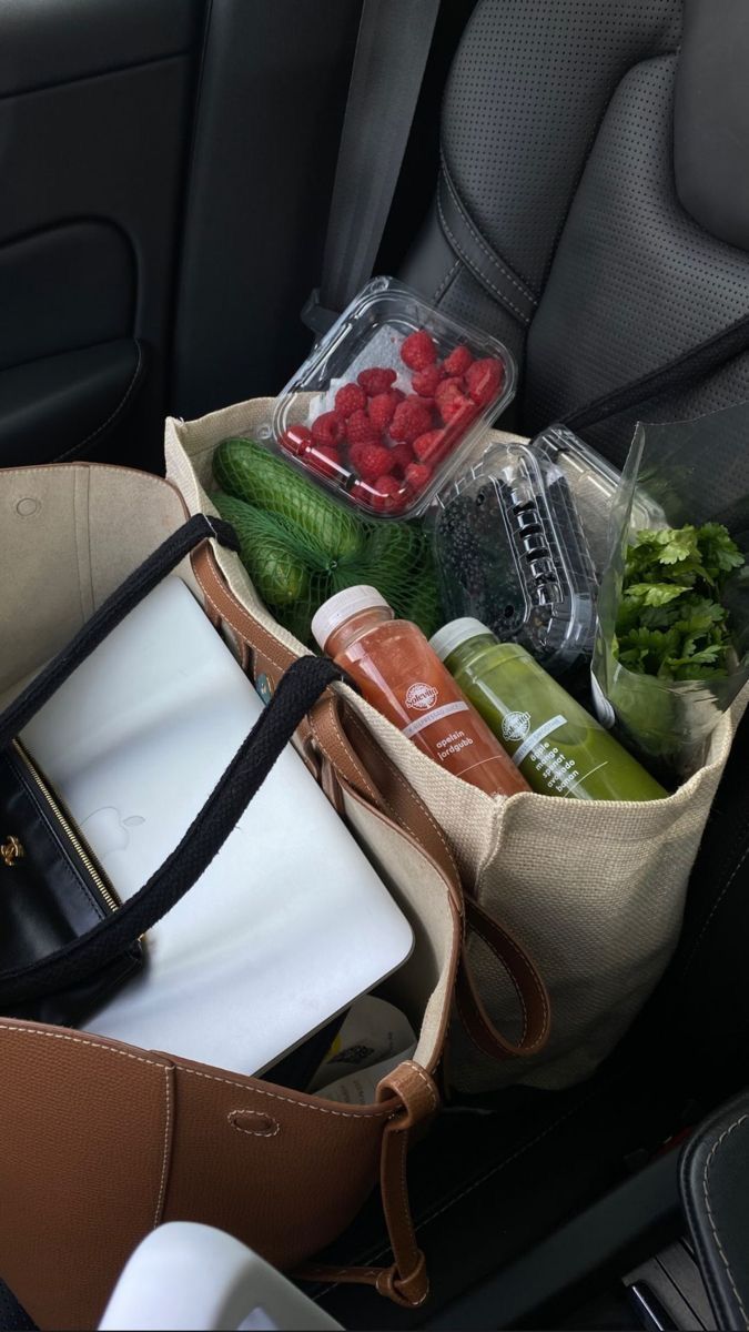 a bag filled with fruits and vegetables sitting in the back seat of a car