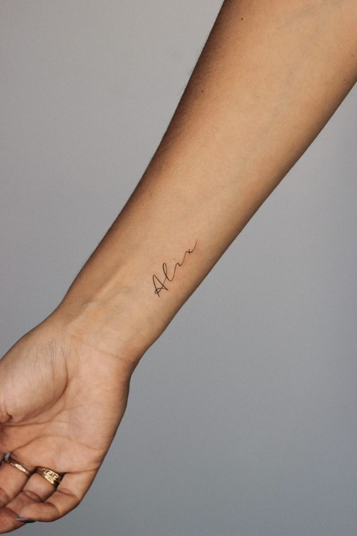 Wrist tattoo small fineline name alix Name Lettering Tattoo Ideas, Childs Name Tattoo Placement, Madden Name Tattoo, Small Wrist Name Tattoo, Dainty Last Name Tattoo, Childs Name Tattoo Ideas For Women Simple, Tattoo For Daughter Name, Dainty Tattoo For Son, Dainty Tattoo For Kids