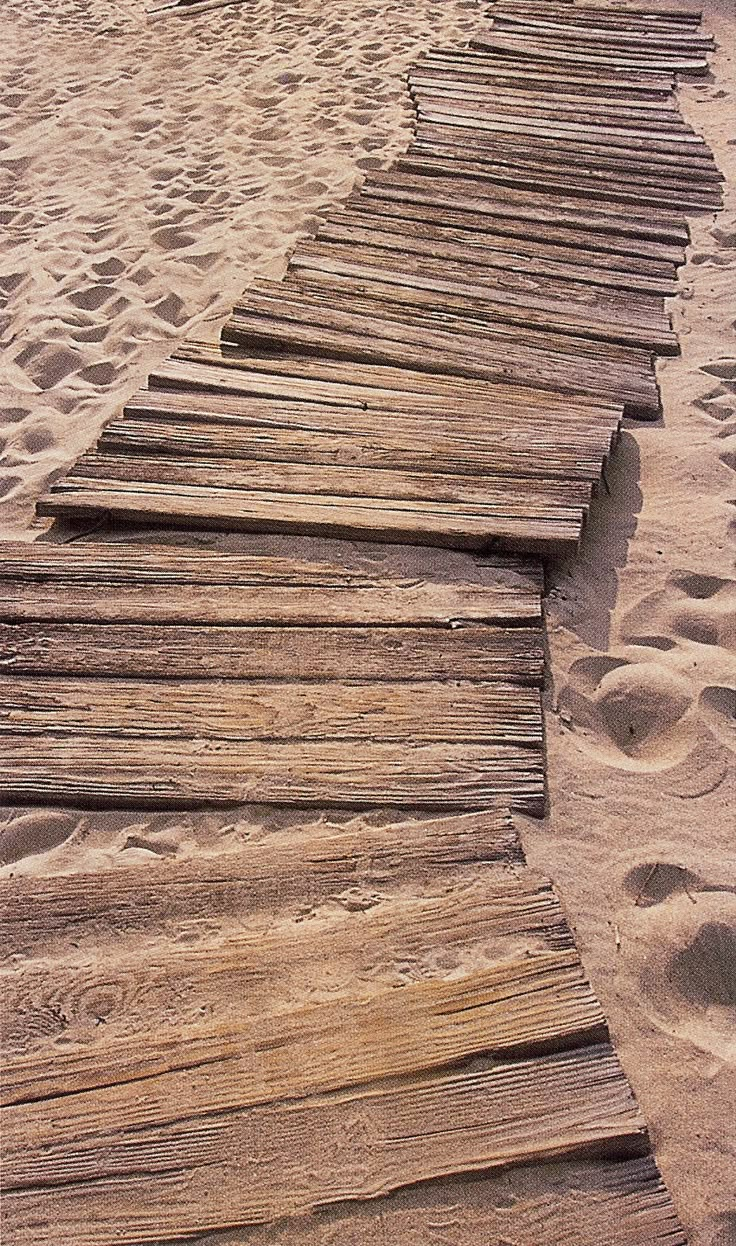 a wooden walkway made out of logs in the sand