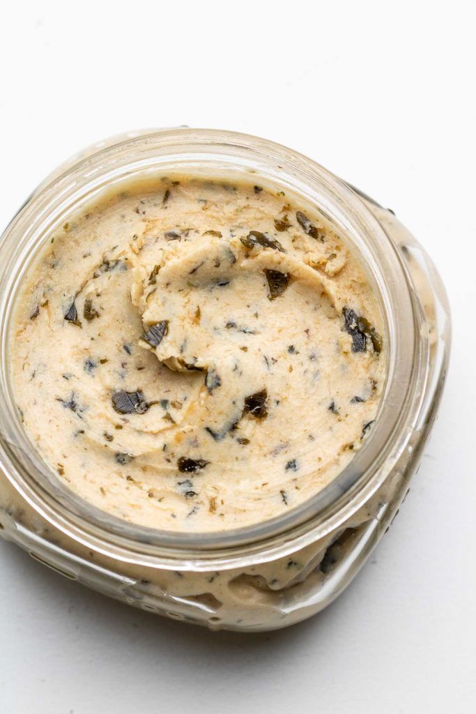 a glass jar filled with food sitting on top of a white table next to a spoon