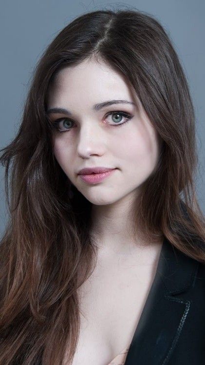 a woman with long brown hair wearing a black blazer and posing for the camera