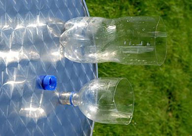 two empty plastic water bottles sitting on top of a metal table with grass in the background