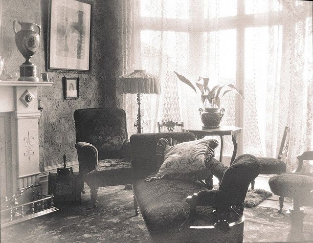 a black and white photo of a living room with two chairs, a table, and a fireplace