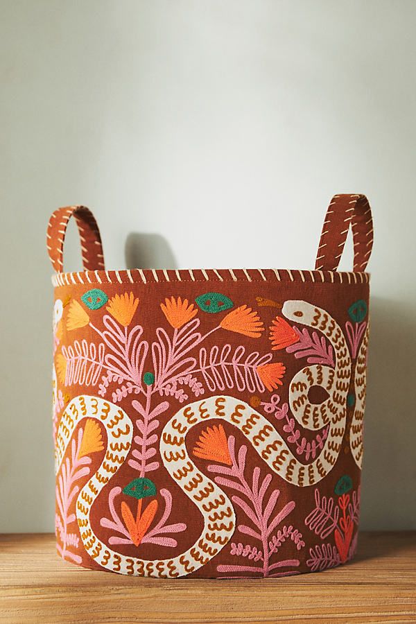 an orange and pink patterned basket sitting on top of a wooden table