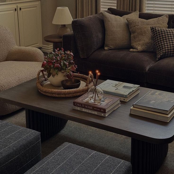 a living room filled with furniture and books on top of a coffee table in front of a window