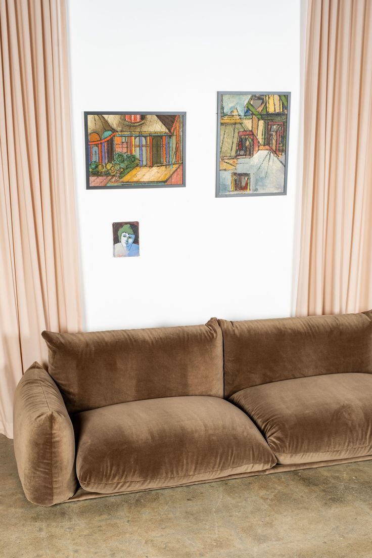 a living room with two paintings on the wall and a couch in front of it