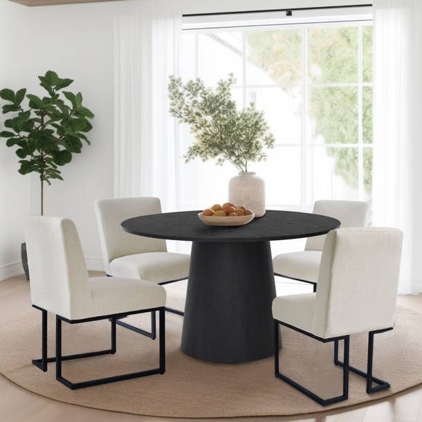 a black table with white chairs around it and a potted plant in the corner