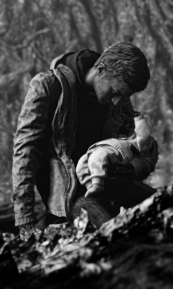 a man kneeling down holding a baby in his hands