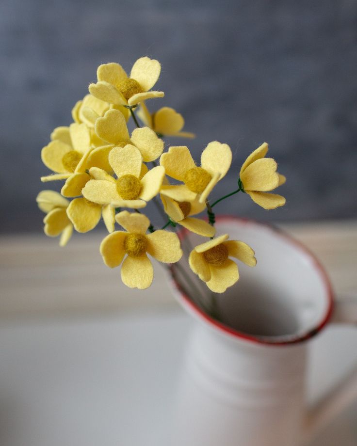 small yellow flowers in a white cup on a table