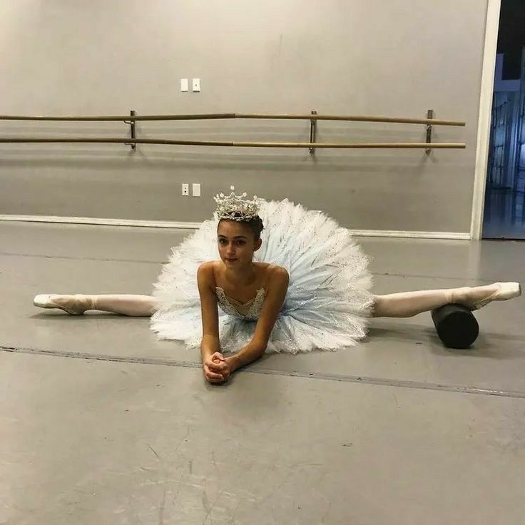 a young ballerina is sitting on the floor