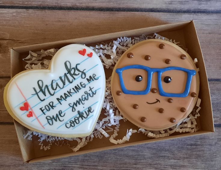 two decorated cookies in a box with writing on them