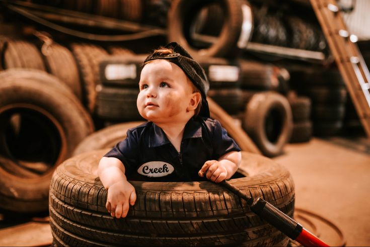 a baby sitting on top of a pile of tires