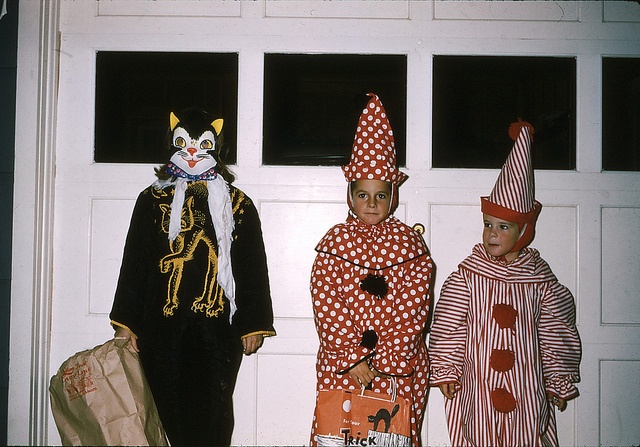 three children dressed up in costumes standing next to a door