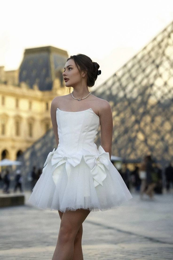 a woman in a white dress is posing for the camera