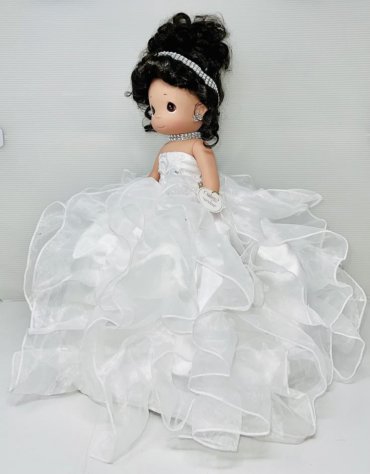 a doll in a white dress sitting on the floor