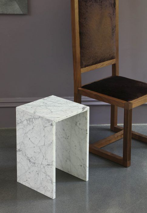 a chair and a stool made out of marble on the floor next to each other