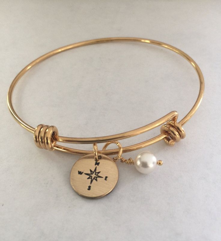 "This listing includes a gold plated stainless steel expandable bangle bracelet with a 1/2\" nu gold discs hand stamped with a compass paired with a Swarovski white pearl. Nu-gold is a copper alloy consisting of 85% copper and 15% zinc. It has a rich warm color and if highly polished resembles gold. This is also known as jewelers brass and will tarnish and need to be polished. What I would like you to know: All of my pieces are hand stamped and made with love just for you. They will arrive in a Expandable Bangle Bracelet, Compass Bracelet, Gold Disc, Gold Charm Bracelet, Friend Wedding, Gold Charm, Compass, Wedding Bridesmaids, Alex And Ani Charm Bracelet