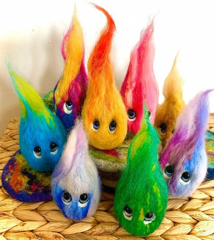 five different colored woolly toy heads sitting on top of a wicker basket