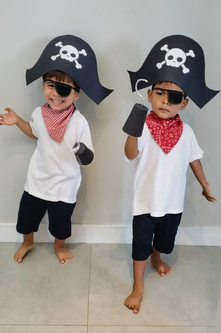 two young boys wearing pirate hats and bandanas, standing in front of a wall