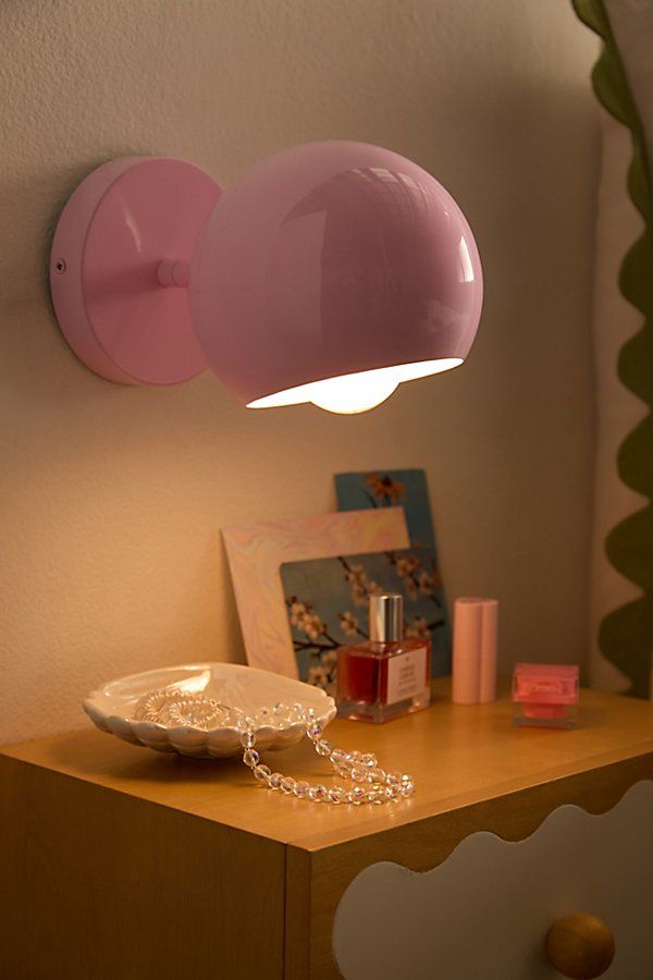 a pink lamp is on the wall next to a white plate and other items in front of it