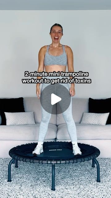 a woman standing on top of a trampoline in front of a white couch