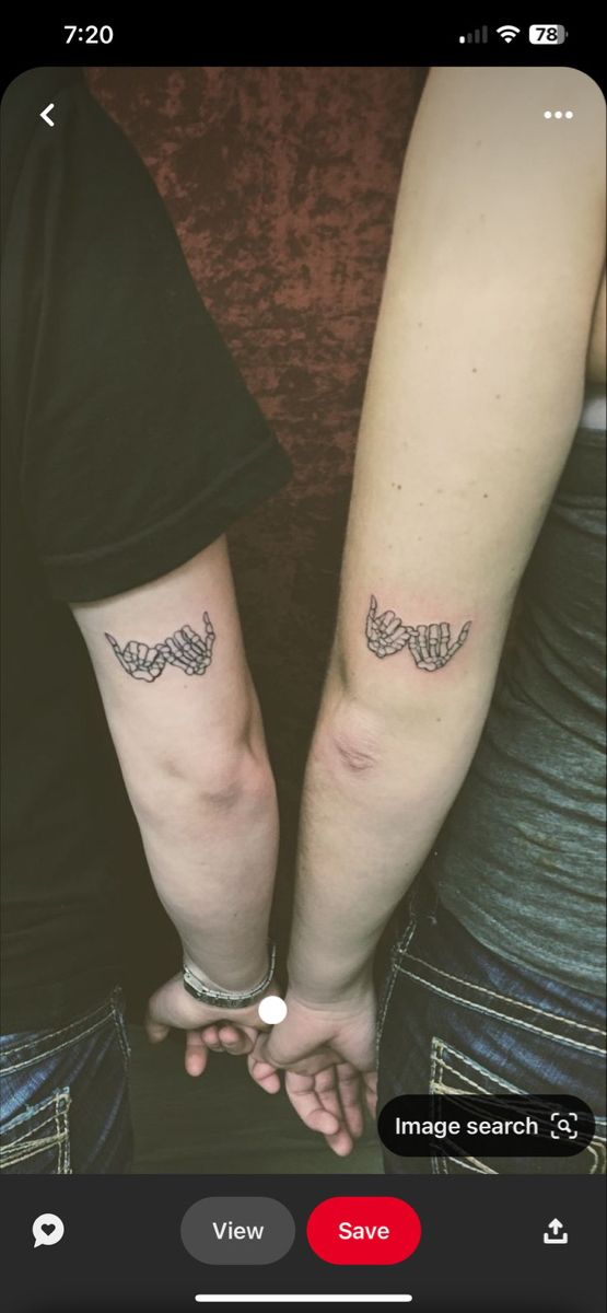 two people holding hands with tattoos on their arms, both showing the same tattoo design