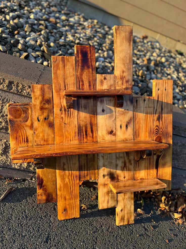 a wooden bench sitting on the side of a road next to some rocks and gravel