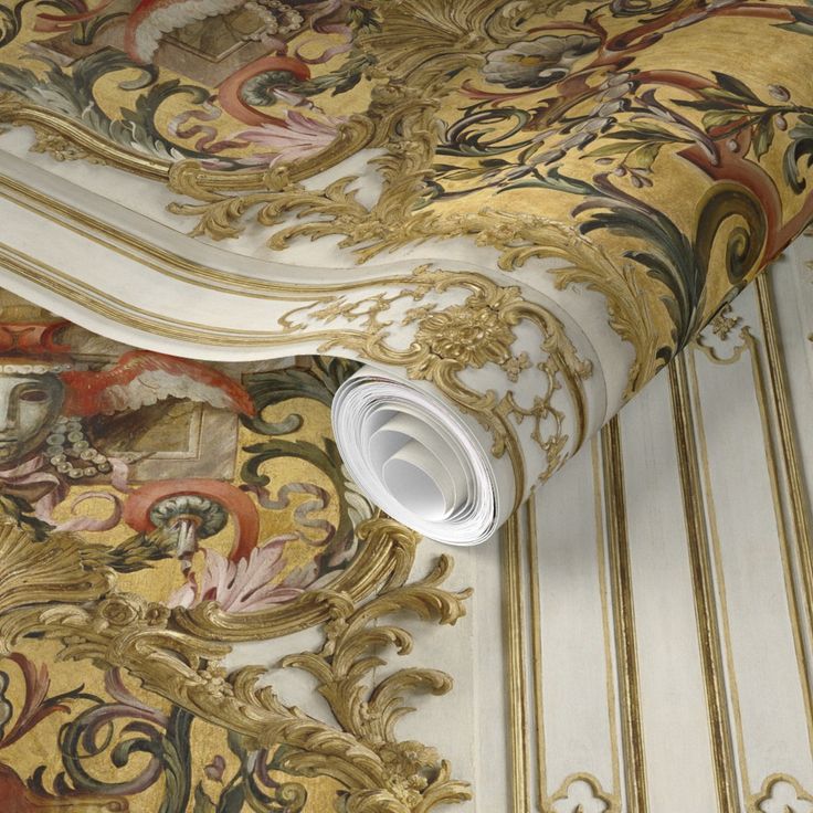 an ornate wallpaper with gold and white designs on it's walls, along with a rolled up roll of toilet paper