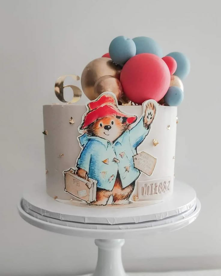 a birthday cake decorated with an image of a paddington bear and lots of colorful balloons