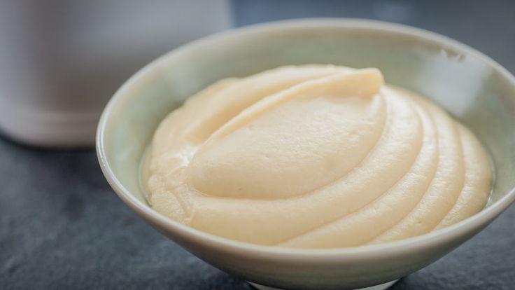 a close up of a bowl of food on a table with a cup in the background