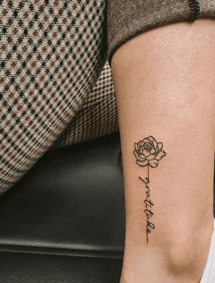 a woman's foot with a rose tattoo on the left side of her leg