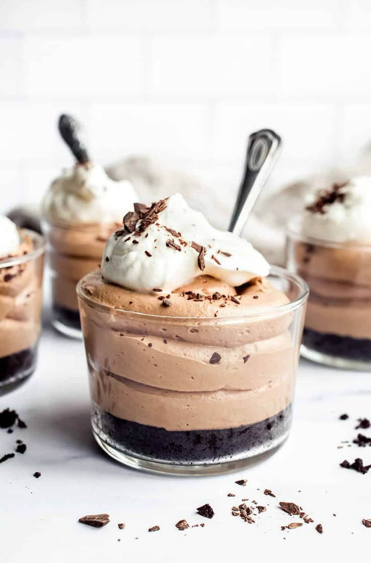 three desserts in small glass dishes with spoons