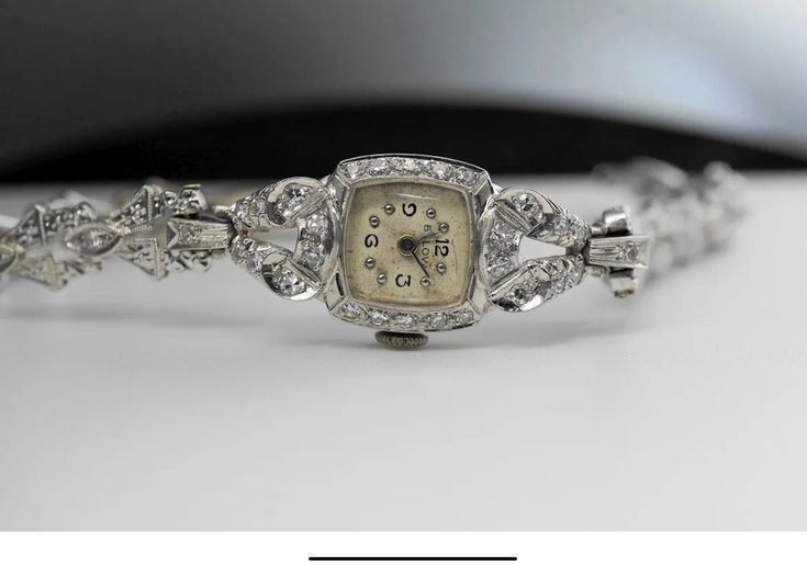 This exquisite Art Deco timepiece from Bulova is a true vintage treasure. Crafted from 14k white gold and adorned with shimmering diamonds, this elegant wristwatch is a stunning addition to any collection. The watch has been expertly maintained and is in exceptional condition, ready to be worn and enjoyed for years to come. A perfect gift for the discerning collector or admirer of vintage jewelry. Art DecoBulova 14k Gold and Diamond watch  Bulova 5ab movement Please refer to photos for condition.All sales are final! Feel free to ask questions ! What you see is what you'll get!  Thank you for your continued business and please check out our other products in the store. We have something for everyone! Stay safe If you have any questions or concerns, contact us.Thank you. Timeless Anniversary Watch With Diamond Accents, Timeless Watches With Diamond Accents For Anniversary, Timeless Diamond Accented Watches For Anniversary, Elegant Evening Diamond Watch With Brilliant Cut, Timeless Diamond Accent Watches For Anniversary, Elegant White Gold Diamond Watch With Brilliant Cut, Elegant White Gold Diamond Watch With Diamond Accents, Timeless Diamond Watches For Formal Occasions, Silver Diamond Watch For Wedding