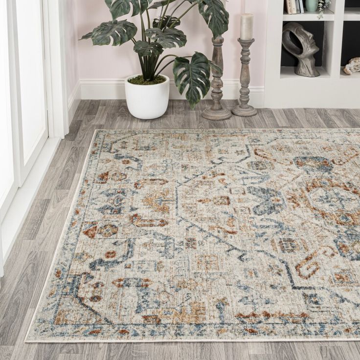 a large area rug with an ornate design on the floor in front of a bookshelf