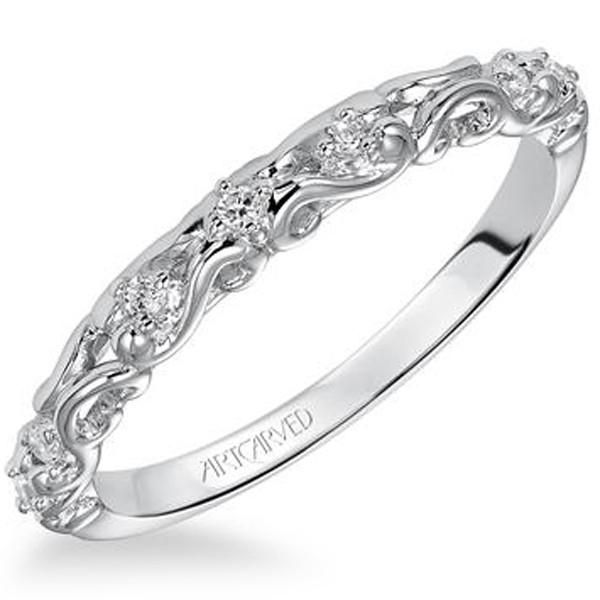 a white gold wedding band with diamonds on the side and an intricate design in the middle