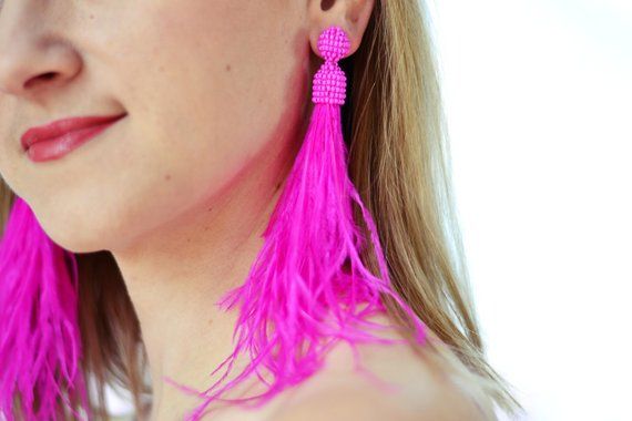 a woman wearing bright pink earrings with long fringes