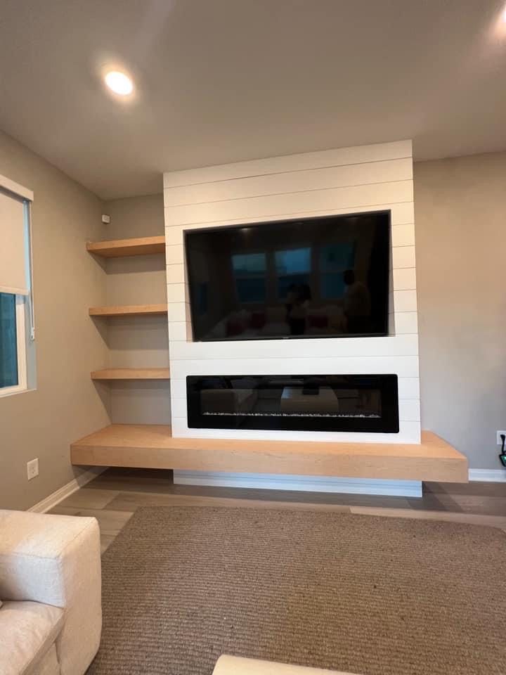 a large flat screen tv mounted on the wall above a fireplace in a living room