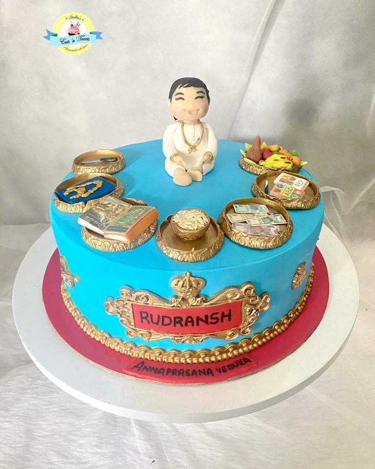 there is a blue cake with gold trimmings on the top and sides that include an image of a man sitting in front of it