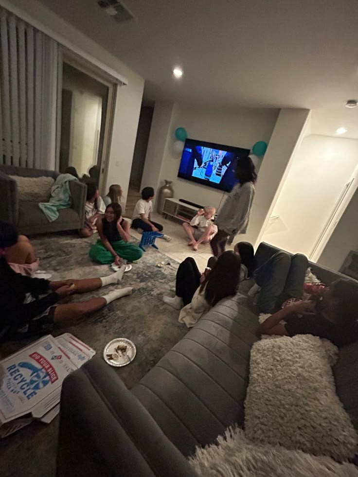 a group of people sitting on top of a couch in a living room next to a tv