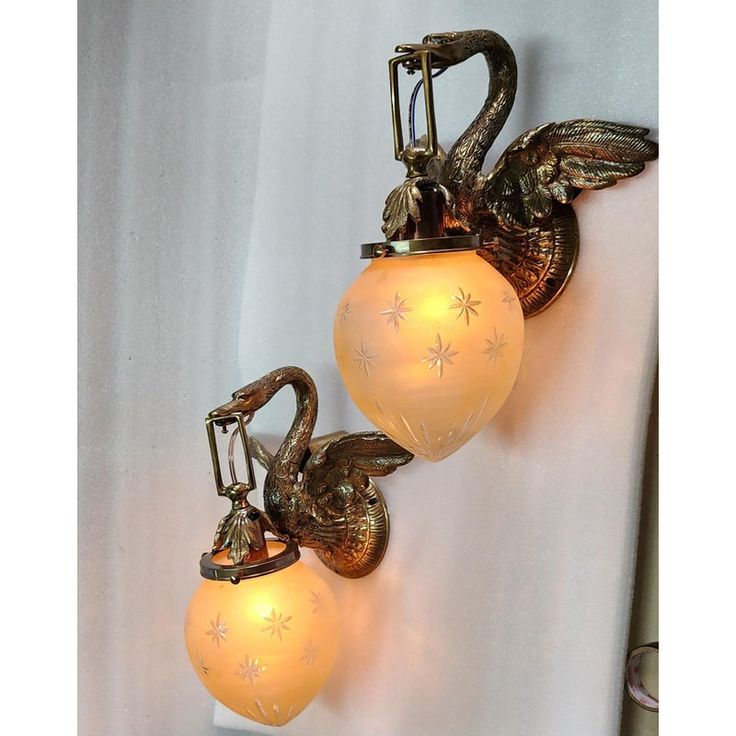 two wall sconces with lights attached to the back of each light, one has an angel's head on it