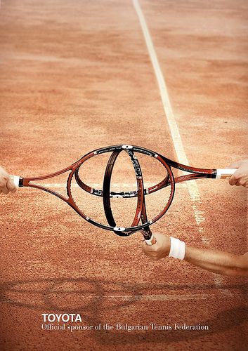 a person holding a tennis racquet on top of a tennis court with the words toyota written on it