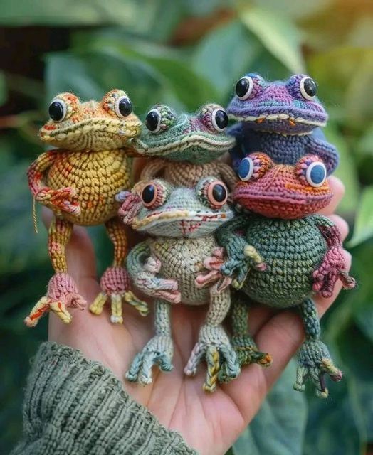 three small stuffed animals sitting on top of someone's hand in front of some plants