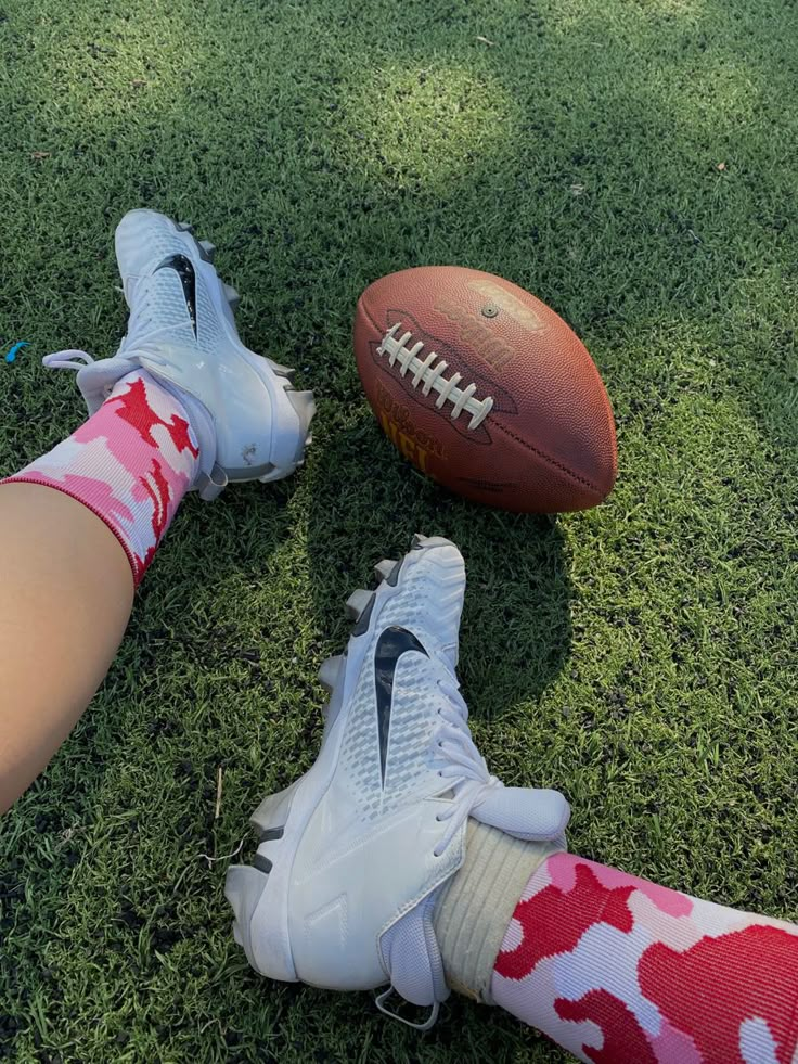 a person laying on the ground next to a football and leg with one foot in the air