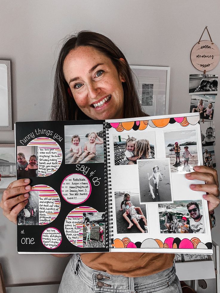 a woman holding up a scrapbook with pictures on it