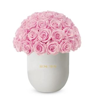 a white vase filled with pink roses