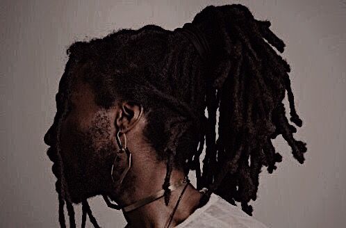 a man with dreadlocks wearing a white t - shirt and silver hoop earrings