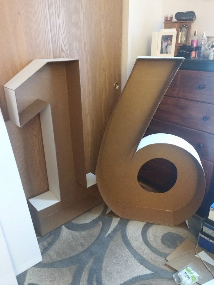 there is a cardboard letter on the floor next to a dresser and bookshelf